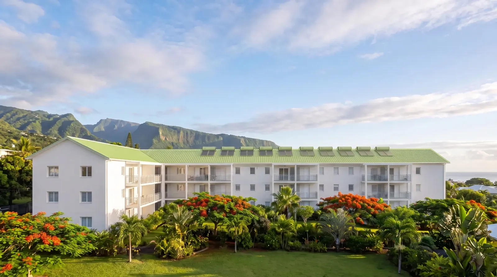 Résidence de logements sociaux rénovée à La Réunion, toiture verte et façade blanche, jardins tropicaux et montagnes en arrière-plan